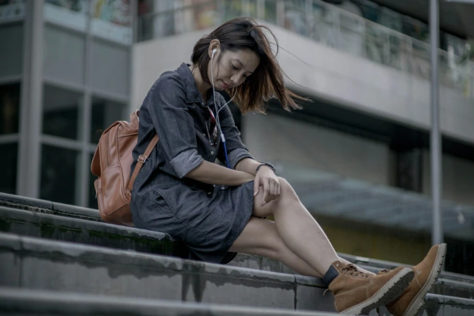 a woman sitting on a ledge using her cell phone